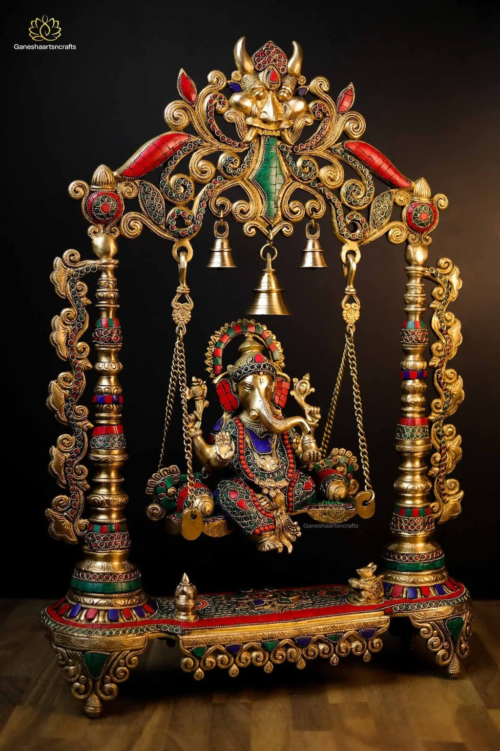 Decorative Ganesh statue on a swing with intricate gold and colored stone detailing.