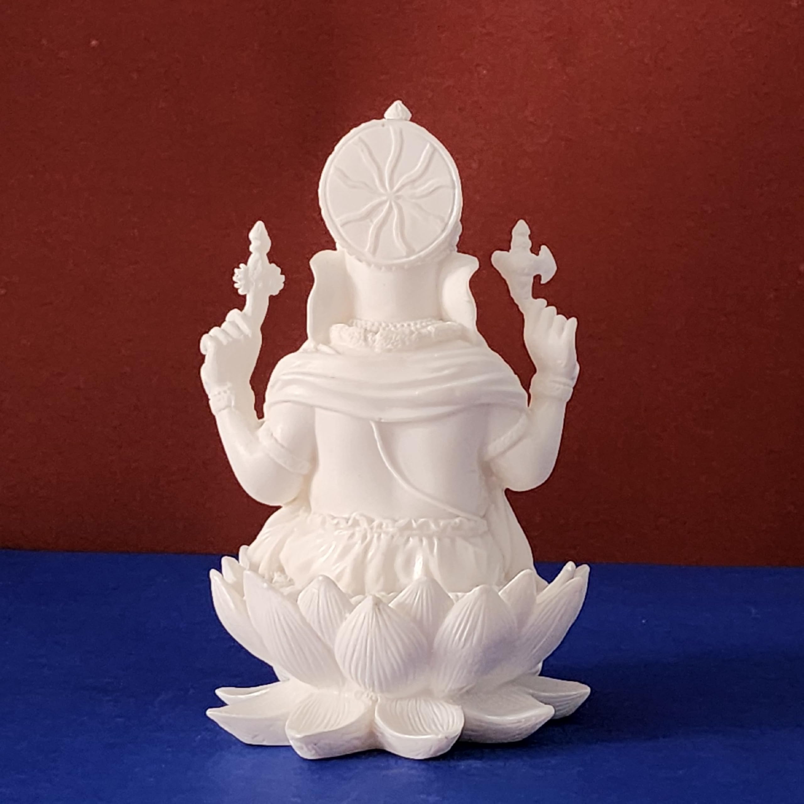 White statue of a seated figure on a lotus flower against a red background