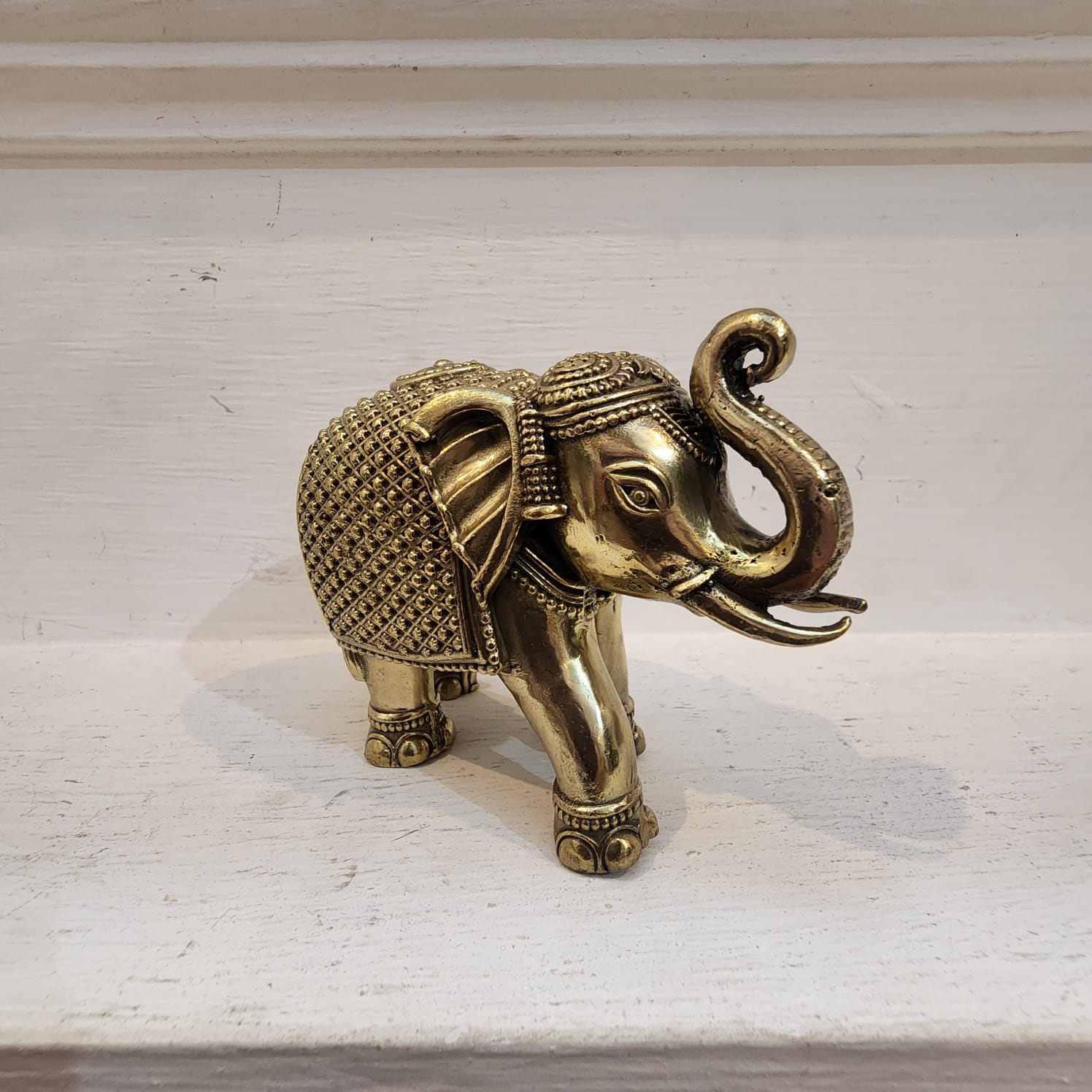 Gold elephant figurine on a light surface