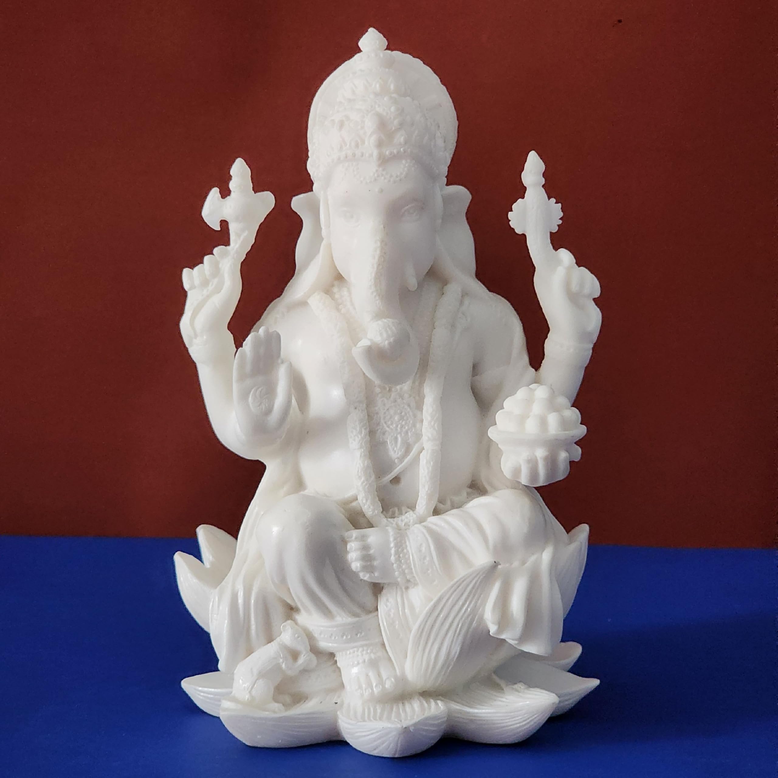 White marble statue of a seated figure on a blue platform with a red background