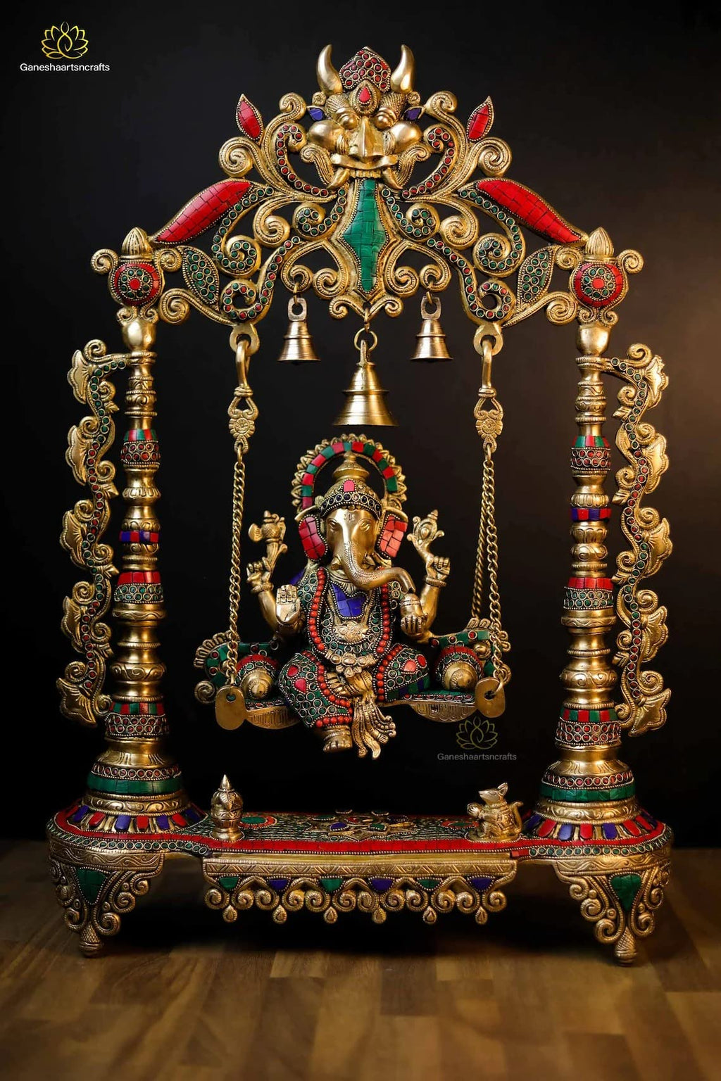 Decorative Ganesh statue on a swing with intricate gold and colored stone detailing.