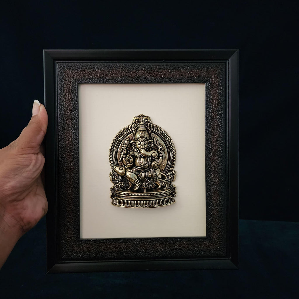 Framed decorative item with a hand holding the frame against a dark background