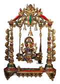 Decorative Ganesh statue on a swing with intricate gold and colored stone detailing.