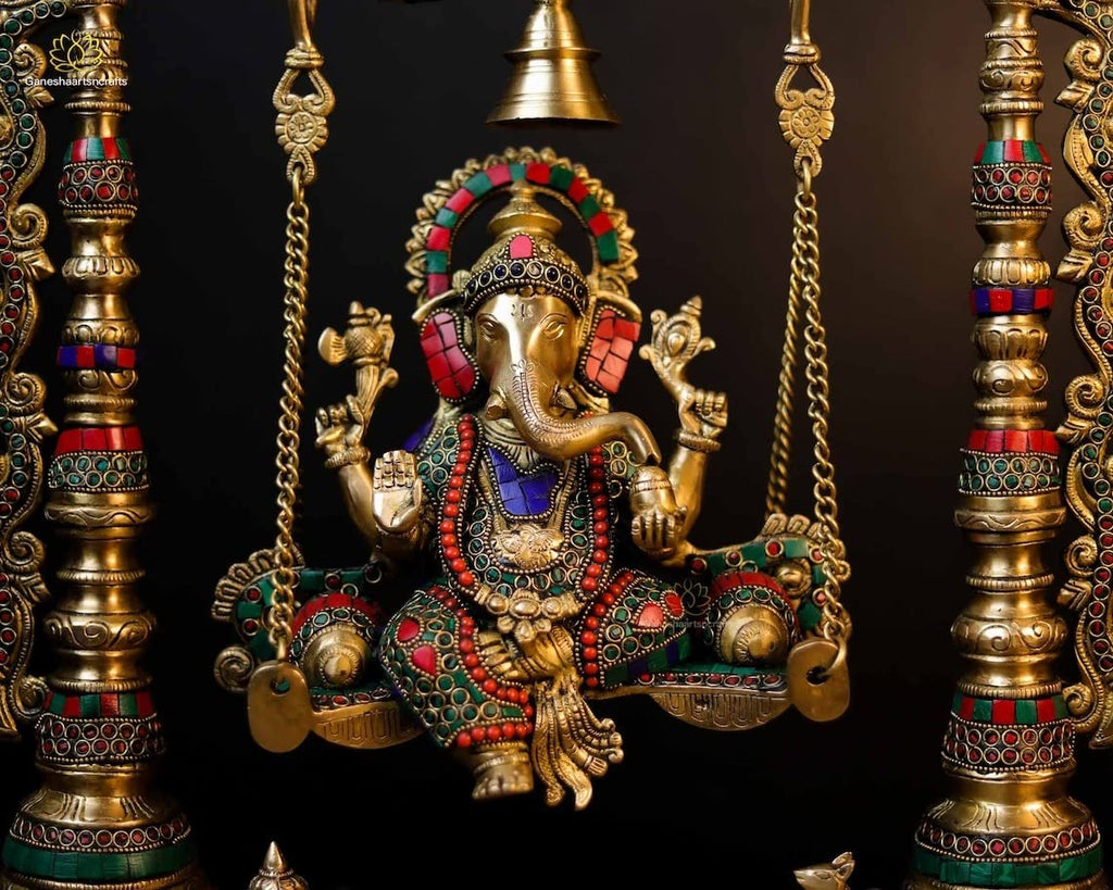 Decorative Ganesh statue on a swing with intricate gold and colored stone detailing.