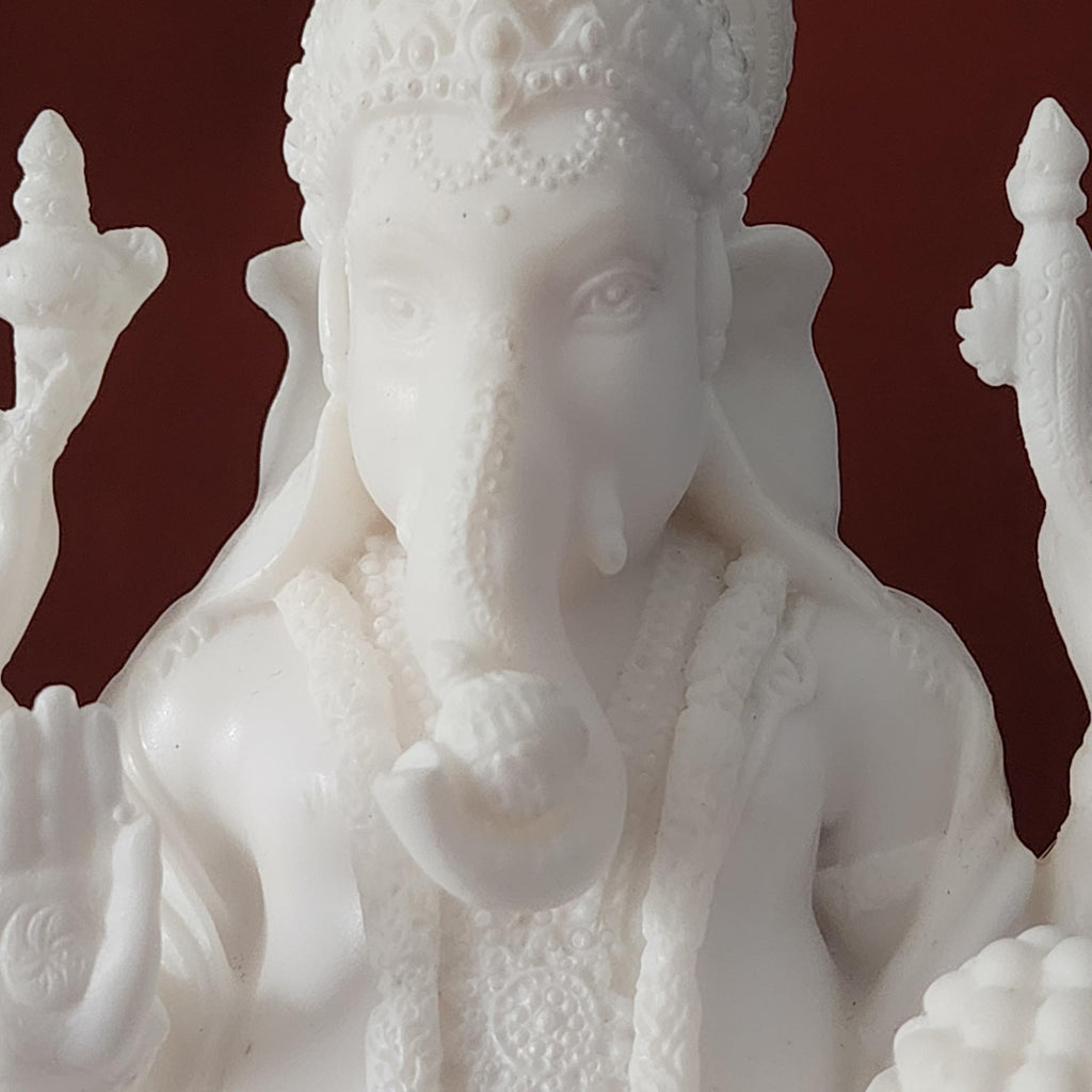 White marble statue of a deity with intricate details on a dark red background